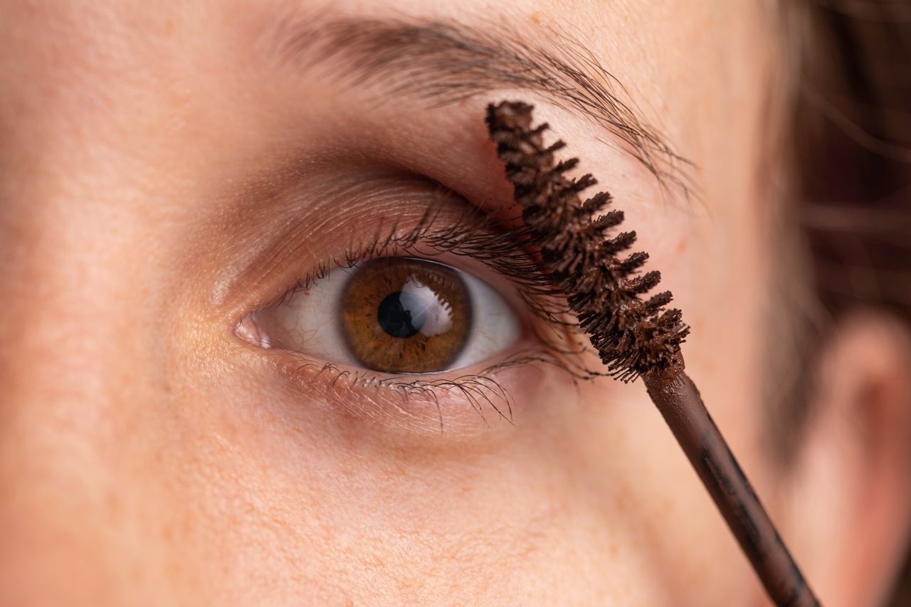 Detailed close-up of an eye applying mascara for makeup enhancement.